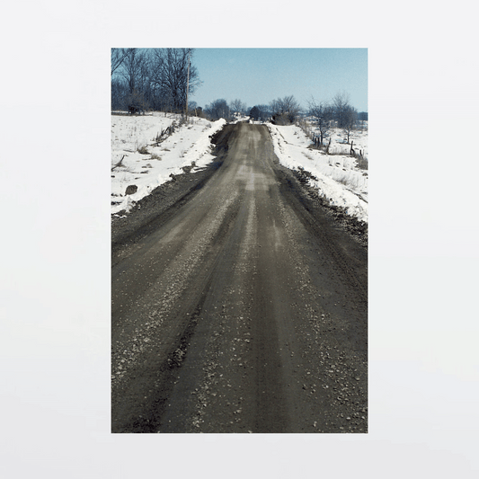Muddy gravel road slices through snow-blanketed family farm